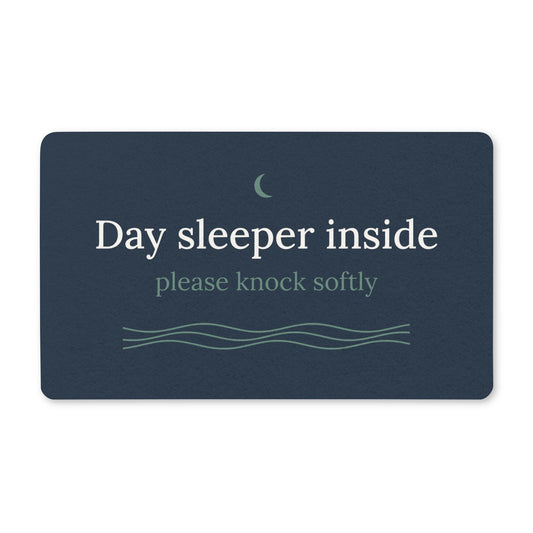 Cove navy doormat reading "Day sleeper inside, please knock softly" with a sage moon and waves